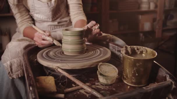 Young woman potter makes faces on a wet clay pot using a tool — 图库视频影像