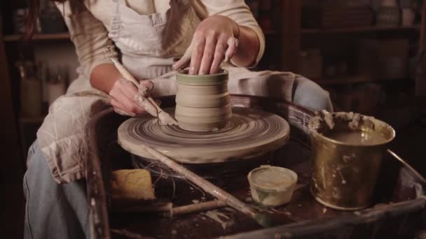 Young woman potter cutting off the excess out of clay pot — Stockvideo
