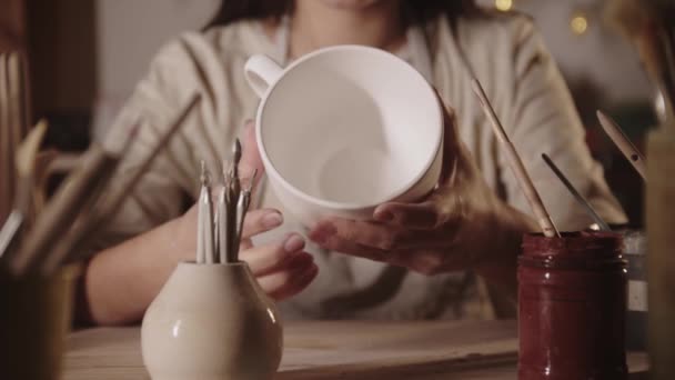 Mujer joven alfarero sosteniendo gran taza de té blanco hecha de arcilla — Vídeo de stock