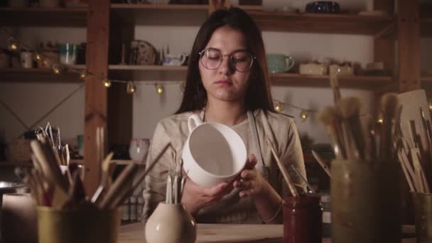 Jeune femme potier tenant grande tasse de thé en céramique blanche — Video