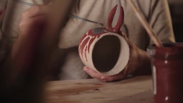 Mladá žena hrnčíř kreslení design na keramický hrnek se štětcem v ateliéru — Stock video