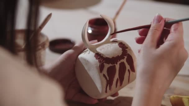 Una mujer alfarera pintando en la taza de cerámica con un pincel — Vídeo de stock