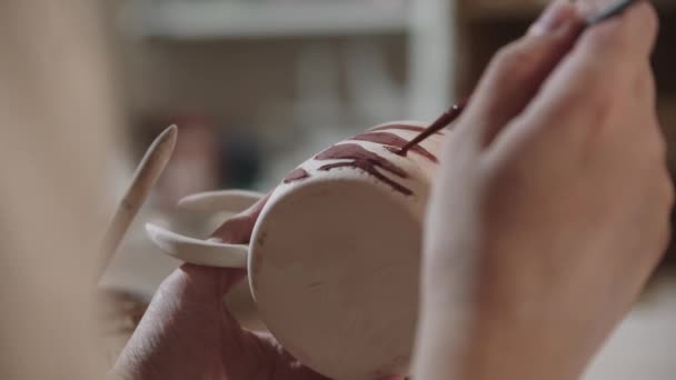 Young woman painting on the ceramic cup with a brush and red color — Stockvideo