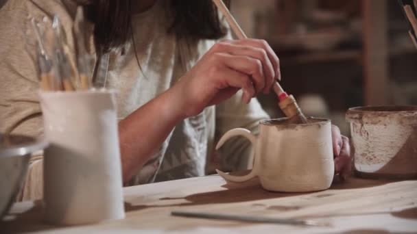 Young woman potter working in art studio - painting the final ceramic product from the inside — 图库视频影像