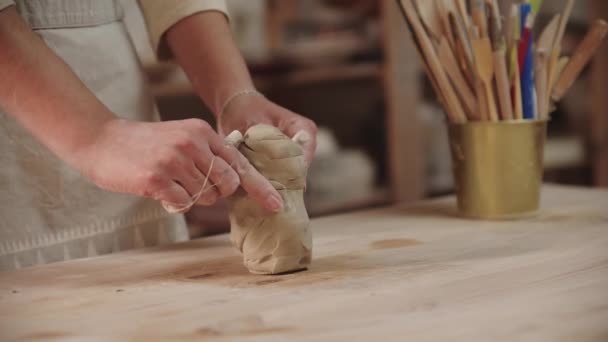 Sanat stüdyosunda çalışan genç bir çömlekçi. İp kullanarak kil parçalarını kesiyor. — Stok video