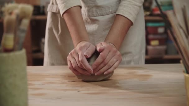 Kadın çömlekçi sanat stüdyosundaki masaya kil yoğuruyor. — Stok video