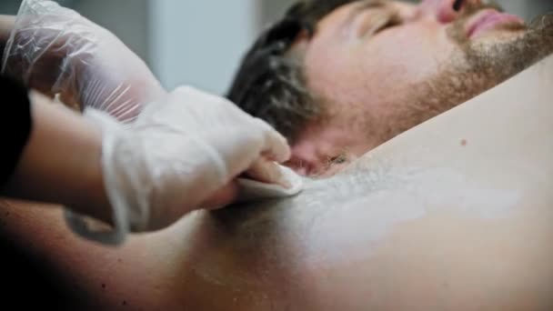 The epilation master applies talc powder on the male armpit — Wideo stockowe