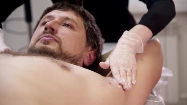 La procedura di cera - il padrone applica la crema calmante della pelle sulle ascelle di clienti maschili — Video Stock
