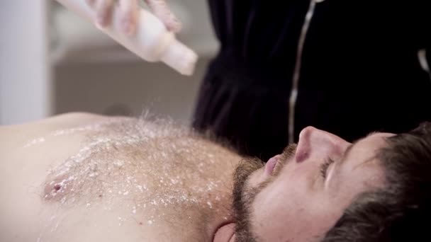 Procedura woskowania - mistrz nakładający talk na klatkę piersiową jej męskiego klienta — Wideo stockowe