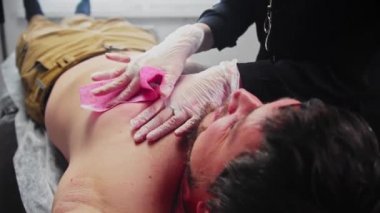 Ağda işlemi. Usta, erkek müşterinin göğsünün sol kısmındaki son kılları alıyor.