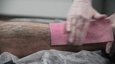 Ağda işlemi. Usta, erkek müşterisinin bacağındaki kılları alıyor.