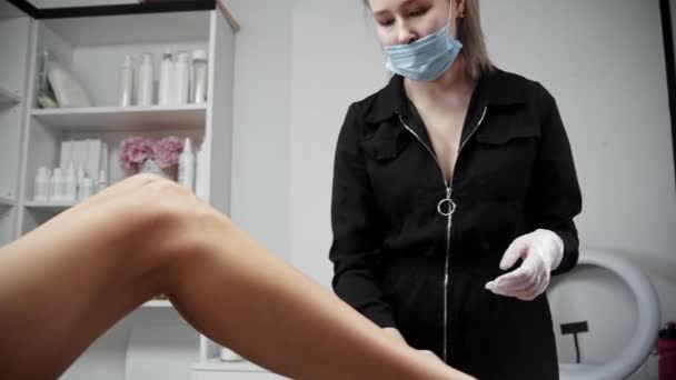 Depileringmästare ta bort överskottet av vax från benen på sin kvinnliga klient — Stockvideo
