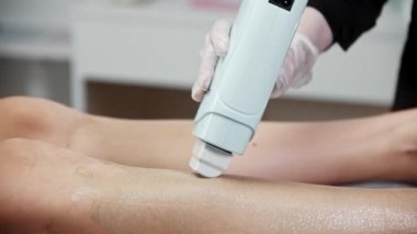 Sürgün ustası kadın müşterisinin bacağına sıcak ağda uyguluyor.