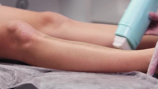 Waxing procedure - the master depilating womans legs using waxing strips - applying hot wax on the skin — стоковое видео