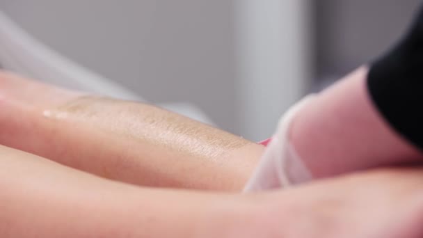 Maestro di cera depilazione gambe delle donne utilizzando strisce di cera — Video Stock