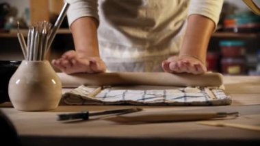 Young woman rolling out the clay using a rolling pin