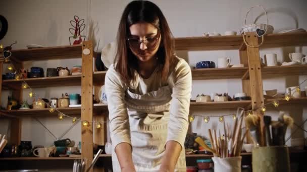 Young woman potter putting the clay in a smooth circle shape — Stok video