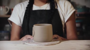 Young woman potter looking at the final clay cup in her hands