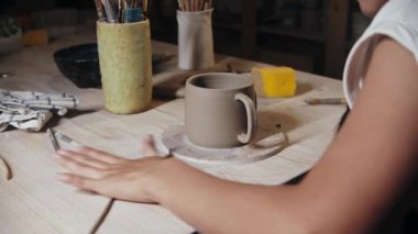 Young woman potter rolling out a small piece of clay
