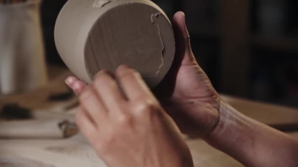 Жінка-гончар відколює мокрий надлишок глини з дна чашки — стокове відео