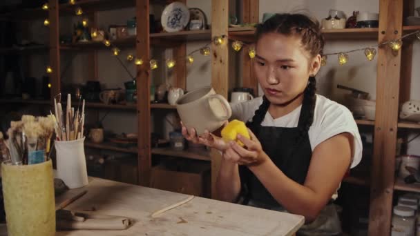 Young woman potter smoothing out the clay cup using a sponge — Stok video