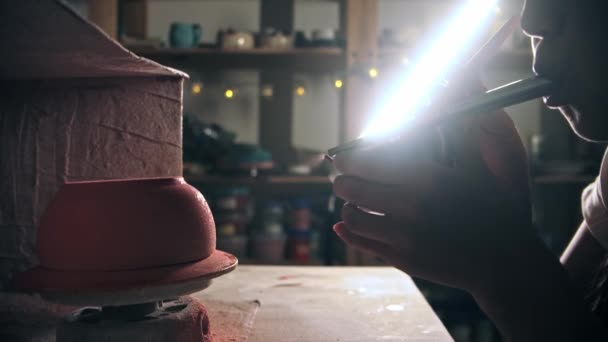 Молода жінка гончар вручну обприскує рожеву фарбу, підірвавши пристрій — стокове відео