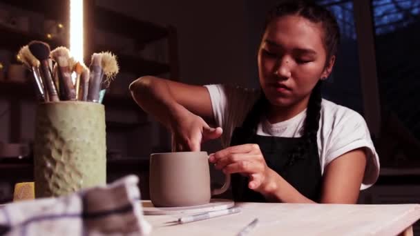 Pottery in the studio - woman potter gluing the handle to a cup — 图库视频影像