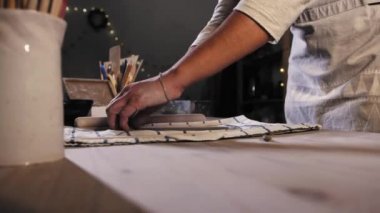 Pottery in the studio - young woman potter preparing a piece of clay