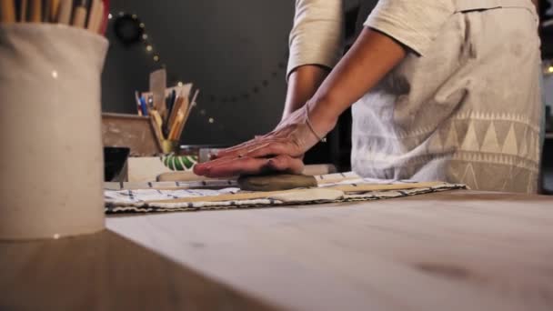 Pottery in the studio - young woman puts the clay on the table and starts kneading it — Stok video