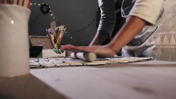 Pottery in the studio - young woman flattening clay using a rolling pin — Vídeos de Stock