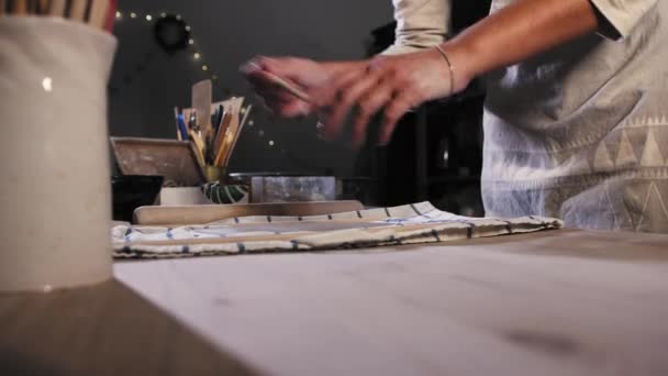 Pottery in the studio - young woman cuts off the excess of the clay using a tool — Video Stock