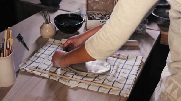 Pottery in the studio - young woman wetting the surface of the flat piece of clay using a sponge — Stockvideo