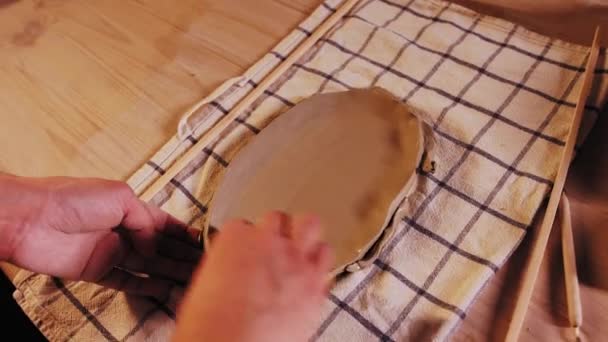 Pottery in the studio - young woman potter wetting the surface of flat piece of clay — Stockvideo