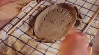 Pottery in the studio - woman makes patterns on a piece of clay
