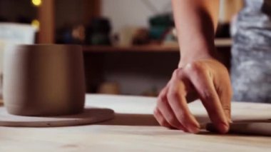 Pottery in the studio - young woman cuts off a small longer piece of clay