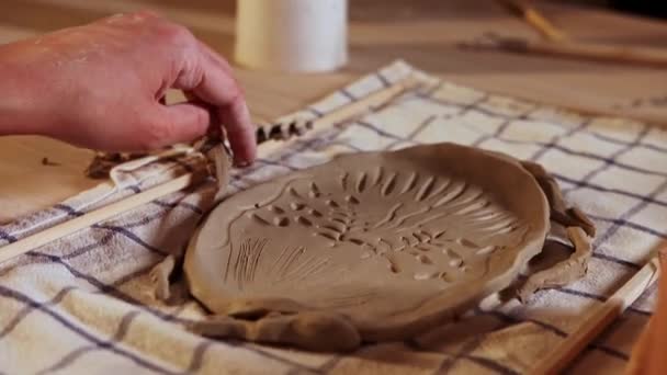 Pottery in the studio - young woman makes patterns on a piece of clay — Stok Video