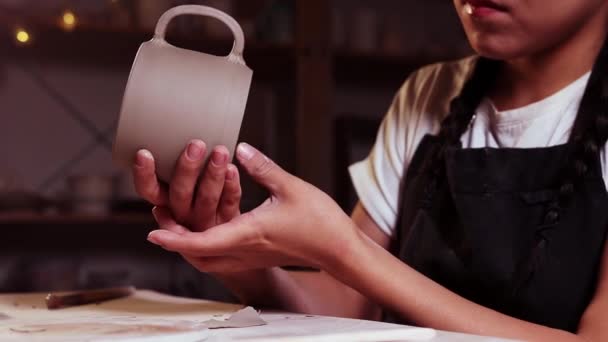 Pottery in the studio - woman potter chipping away the wet excess of the clay from the bottom of a cup — Stok video