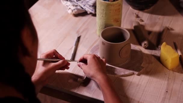Pottery in the art studio - woman potter makes ribs on the handle seam for attaching it to the cup — Vídeo de Stock