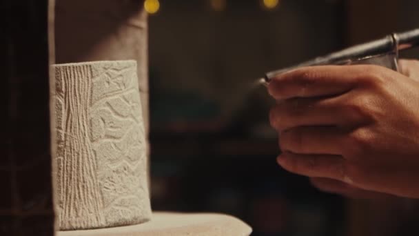 Pottery in the studio - potter manually sprays white powder paint on the clay cup — Stock Video