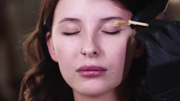 Aplicando cera sob a sobrancelha em uma mulher bonita — Vídeo de Stock