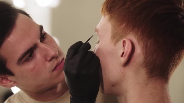 Un maître des sourcils qui travaille avec les sourcils de son client masculin — Video