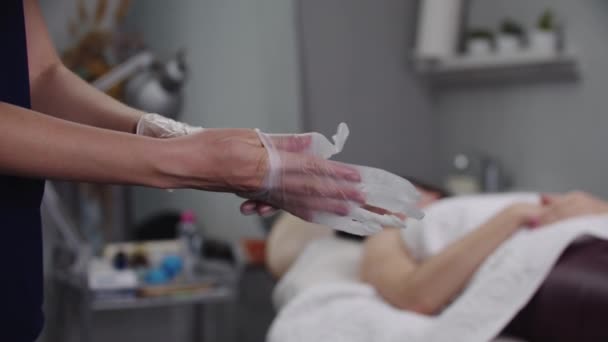 Žena masagistka si před zahájením procedury nasadí rukavice — Stock video
