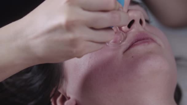 Massageassistentin mit einem kleinen Vakuumgerät auf der Wange ihrer Kundin — Stockvideo