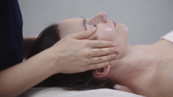 Massagiste femme faisant un massage du visage en utilisant ses doigts sur la peau propre de sa cliente — Video