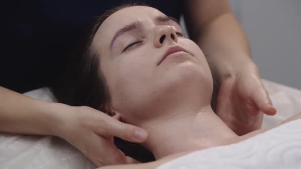 Massagist gör avslappning i nacke och axlar med händerna på sin kvinnliga klient — Stockvideo