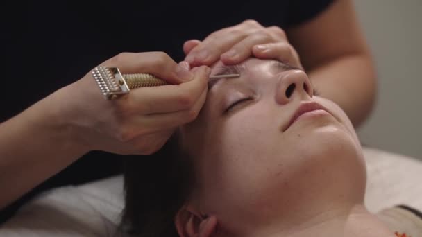 Masagist împingând pe punctele sub fruntea clientului ei de sex feminin folosind un instrument — Videoclip de stoc