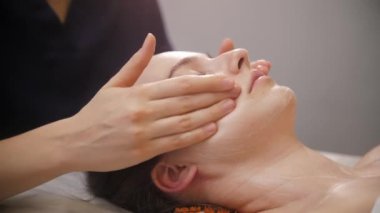 Yüz masajı. Kadın müşterileriyle çalışan masajcı. Parmaklarını kullanıyor.