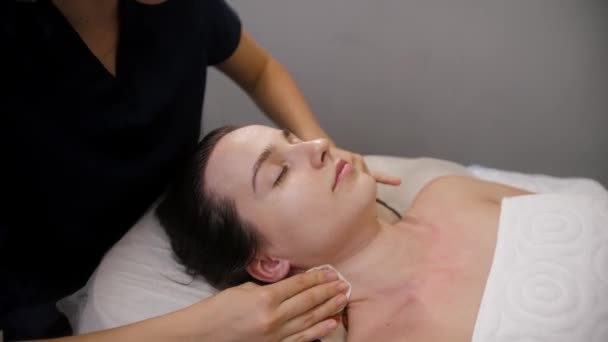 Massagem facial - a massagista esfregando o rosto de seu cliente feminino com as almofadas de algodão antes do procedimento — Vídeo de Stock