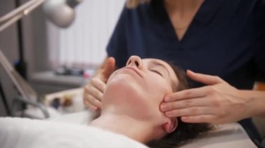 Masaj seansı. Masajcı kadın müşterisinin cildine krem sürüp yüzüne sürmüş.