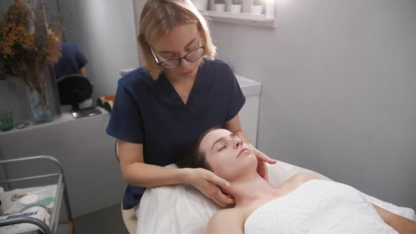 La sesión de masaje - el masajista que relaja el cuello y los hombros de su cliente femenino — Vídeo de stock